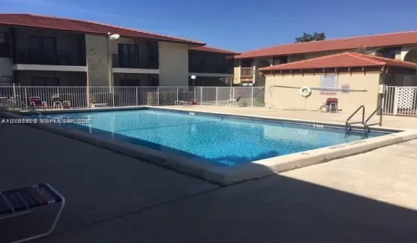 Rectangular swimming pool featuring a concrete deck, perimeter fencing, and metal entry handrails