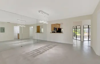 Large-format mirror wall with a crystal-accented chandelier, expansive tile flooring, pass-through kitchen opening, and multi-pane black-frame glass doors