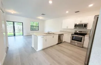Kitchen featuring white cabinetry, light-toned countertops, stainless steel appliances, recessed lighting, and wood-finish flooring