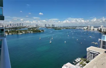 Panoramic water and city skyline outlook featuring a wide expanse of bay, anchored boats, and distant high-rise architecture