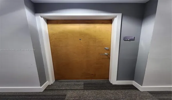 Solid-core wood-finish door with brushed metallic hardware, integrated security peephole, and white architectural casing