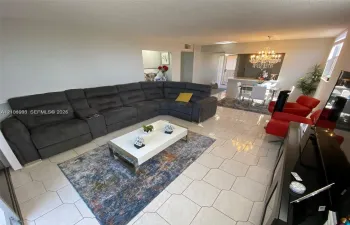 Open-concept interior featuring light-toned tile flooring, recessed ceiling lighting, and a chandelier-style fixture