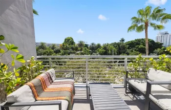Private balcony featuring horizontal metal railing and mature tropical greenery