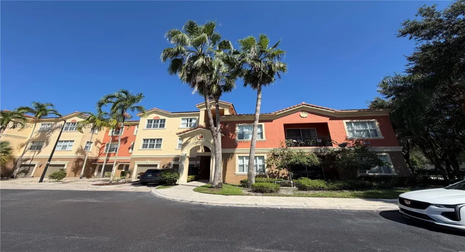 Multi-story stucco exterior featuring a Mediterranean-inspired architectural style, tile roof, arched entryway, and integrated garage doors