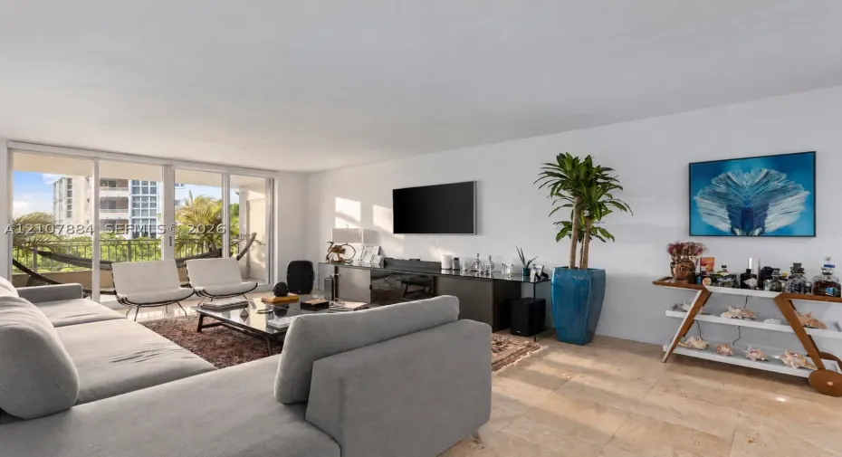 Living area featuring neutral stone flooring, floor-to-ceiling glass sliding doors, and access to a balcony with metal railings
