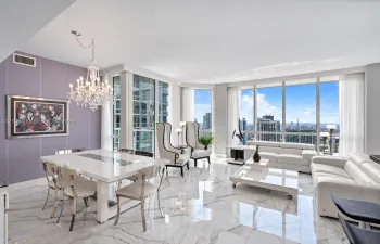 Expansive living area with large floor-to-ceiling windows, polished marble-look flooring, and a crystal chandelier