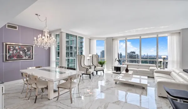 Expansive living area with large floor-to-ceiling windows, polished marble-look flooring, and a crystal chandelier