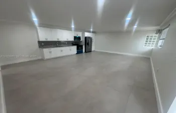 Open-concept space featuring large-format tile flooring, white shaker-style cabinetry, stone-surface countertops, recessed lighting, and a glass block window