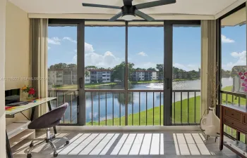 Enclosed sunroom featuring floor-to-ceiling windows, sliding glass doors, tile flooring, and a ceiling fan