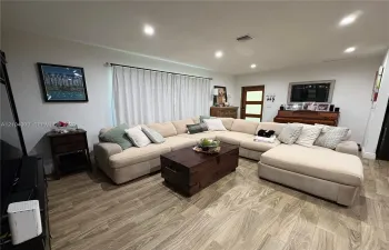 Living area featuring wood-finish flooring, recessed lighting, and a multi-pane glass entry door