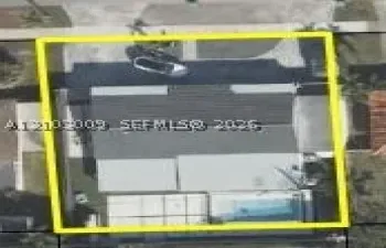 Aerial perspective of a property lot featuring a single-story structure, a paved driveway, and an in-ground swimming pool
