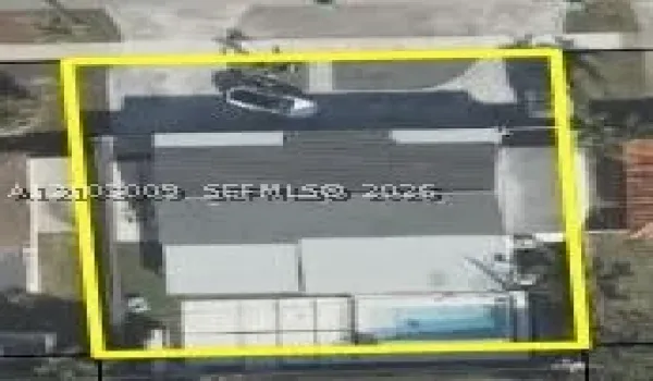 Aerial perspective of a property lot featuring a single-story structure, a paved driveway, and an in-ground swimming pool