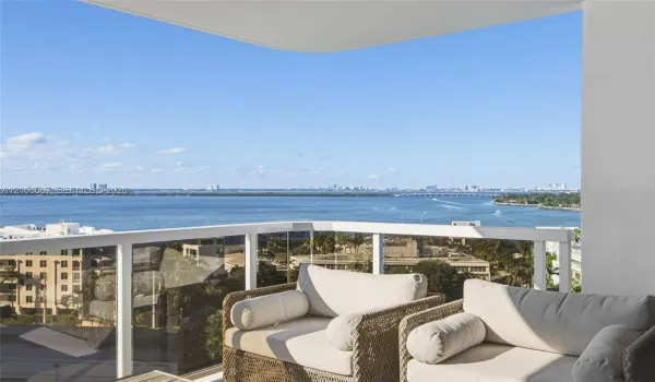 Private balcony featuring a white metal railing with glass panels and expansive water surroundings