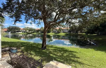 Waterfront lot featuring a natural pond, decorative fountain, mature shade trees, and manicured grass grounds