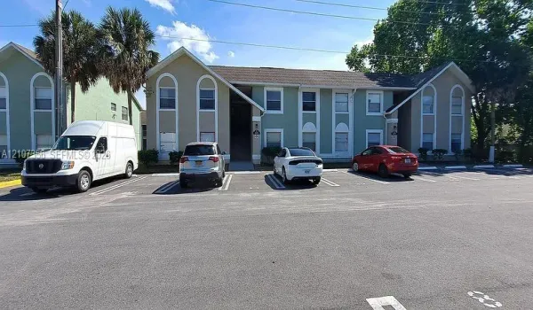 Two-story exterior facade featuring light-toned stucco finish, arched window accents, and paved off-street parking (2 Assigned Parking Spots)