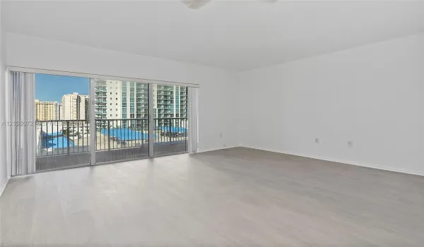 Open-concept interior featuring light wood-finish flooring, sliding glass balcony doors, and a metal-railed balcony