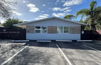 Exterior facade featuring stone veneer detailing, wide-eave roofline, and dedicated parking spaces bordered by privacy fencing