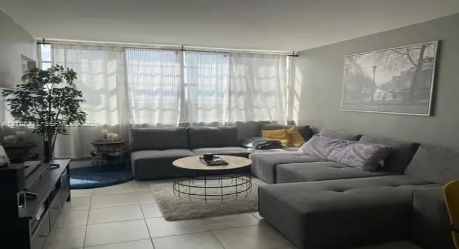 Living area featuring large-format ceramic tile flooring and floor-to-ceiling windows