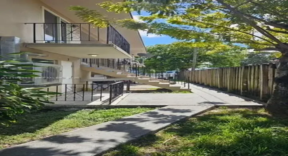 Multi-level exterior featuring a concrete staircase, upper-level balcony with metal railing, ground-level patio, and wood-panel fencing