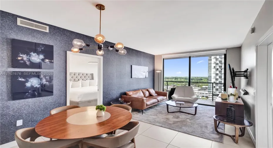 Floor-to-ceiling windows, textured accent wall, multi-light modern chandelier, and tile flooring