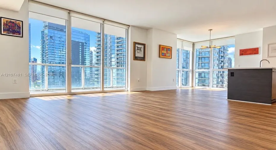Floor-to-ceiling windows, wood-finish flooring, and kitchen island with a built-in sink