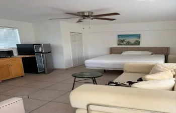 Room featuring ceramic tile flooring, built-in wooden cabinetry, louvered closet doors, and a ceiling fan