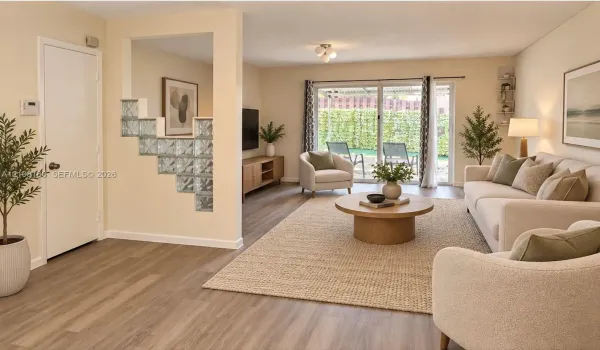 Living area featuring wood-finish flooring, a decorative glass block partition, and sliding glass doors providing outdoor access