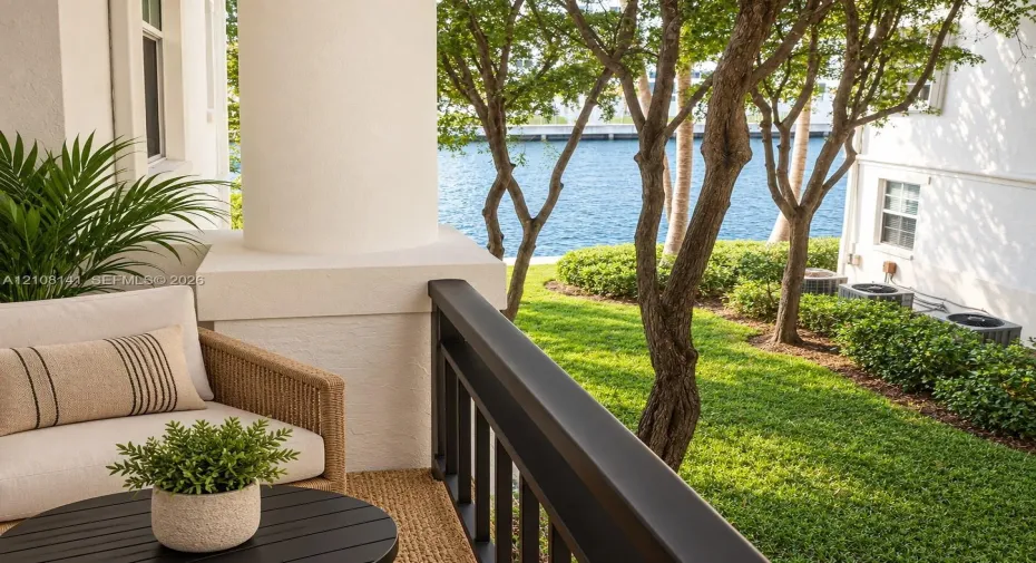 Covered patio featuring a structural column, dark-finish metal railing, manicured lawn, and water side-frontage