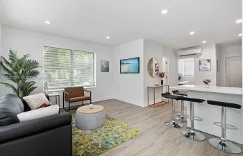 Open-concept living room with modern kitchen and wood-look flooring.