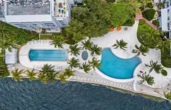 Waterfront community amenities featuring a lap pool, a free-form pool, a spa, expansive sun decks, and mature tropical landscaping