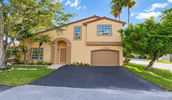 Stucco exterior featuring an arched entryway, attached garage with paneled door, and multi-paned windows