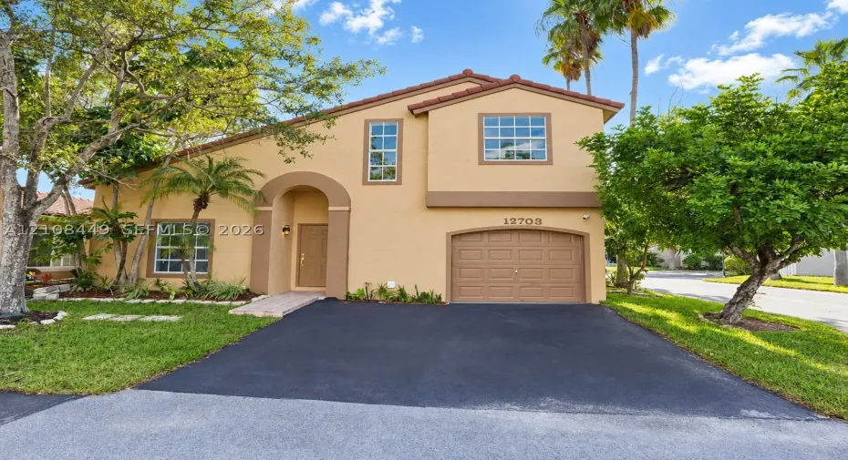 Stucco exterior featuring an arched entryway, attached garage with paneled door, and multi-paned windows