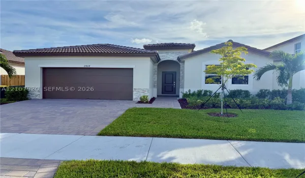 Single-story residence featuring a tile roof, exterior stone accents, a multi-car garage, and a paved driveway