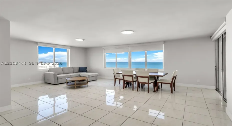 Open-concept living space featuring high-gloss tile flooring, floor-to-ceiling windows, and panoramic ocean water scenery