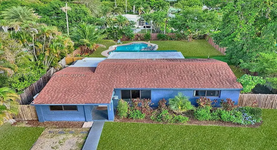 Single-story residence featuring a shingled roof, stucco exterior, rear swimming pool, and wood-paneled privacy fencing