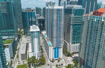 High-rise tower featuring a prominent vertical blue architectural accent, exterior balcony levels, and an elevated rooftop swimming pool