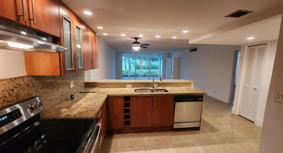 Kitchen featuring wood cabinetry, stone countertops, stainless steel appliances, a built-in wine rack, and recessed lighting