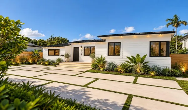 Modern residence featuring a horizontal lap siding exterior, a multi-tonal concrete paver driveway with turf accents, a flat metal roof, and dark-framed windows