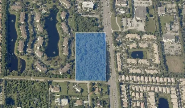 Rectangular parcel of undeveloped land featuring mature tree cover and direct frontage to a paved thoroughfare