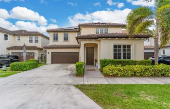 Stucco exterior featuring a clay tile roof, arched entryway, multi-panel garage door, and solar panels
