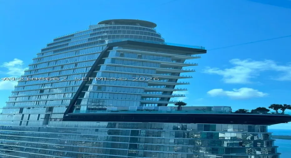 Contemporary high-rise architecture featuring a glass curtain wall, cantilevered design, multi-level terraces, and integrated rooftop landscape elements