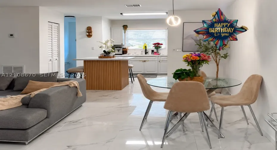 Kitchen featuring white shaker-style cabinetry, a vertical-slat kitchen island with a white countertop, and polished tile flooring