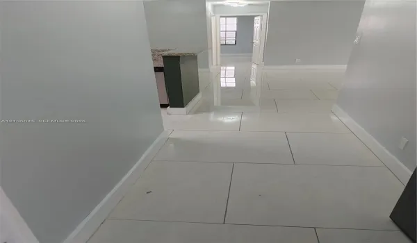 Large-format polished tile flooring featuring a neutral finish and a peninsula with a stone-composite countertop