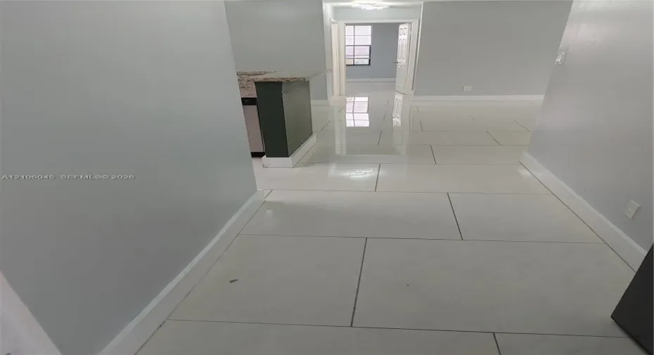 Large-format polished tile flooring featuring a neutral finish and a peninsula with a stone-composite countertop