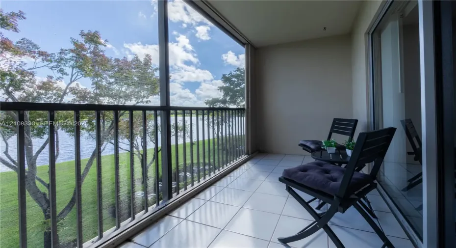 Screened-in balcony featuring tile flooring, metal railings, and direct water frontage