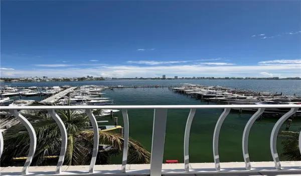Elevated balcony with vertical metal railing overlooking a private marina and wide-water expanse