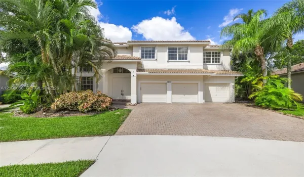 Two-story residence featuring a tile roof, stucco exterior, three-car garage, and paver driveway