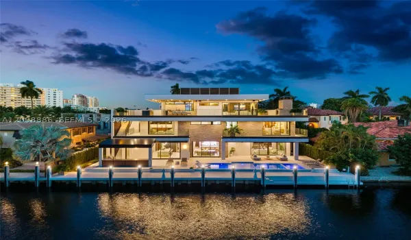 Three-story modern waterfront residence featuring a private boat dock, multi-level terraces with glass railings, stone veneer accents, and a rectangular swimming pool