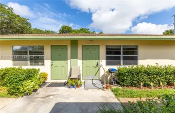 Exterior view featuring stucco siding, aluminum-frame windows, dual entry doors, and a concrete walkway