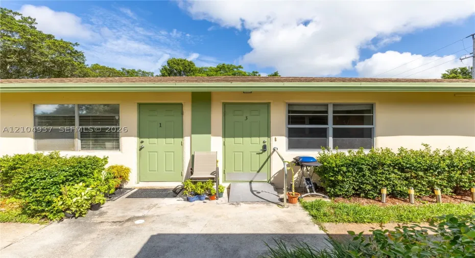 Exterior view featuring stucco siding, aluminum-frame windows, dual entry doors, and a concrete walkway